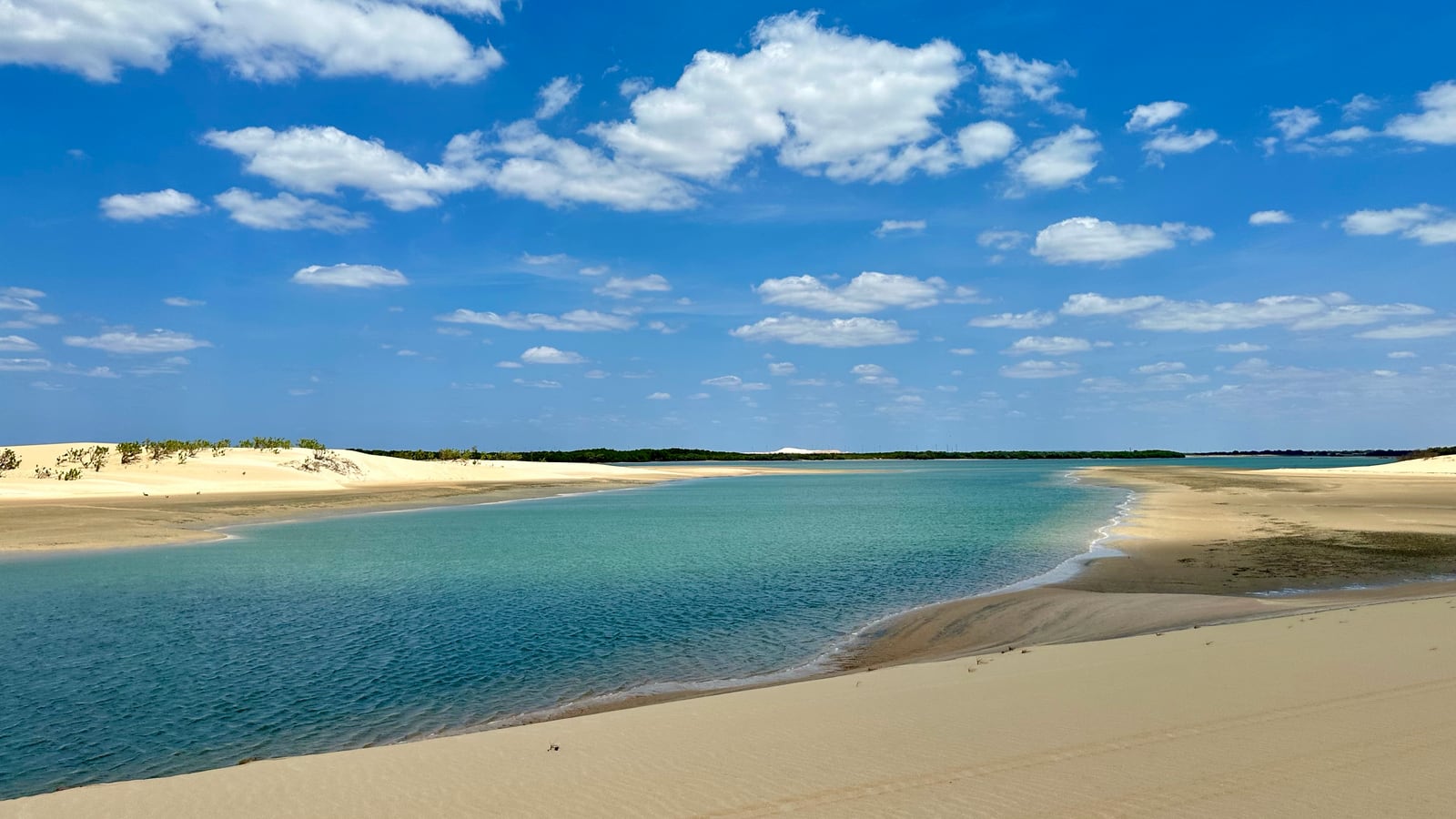 Uma faixa de areia branca separando o mar turquesa de uma lagoa calma